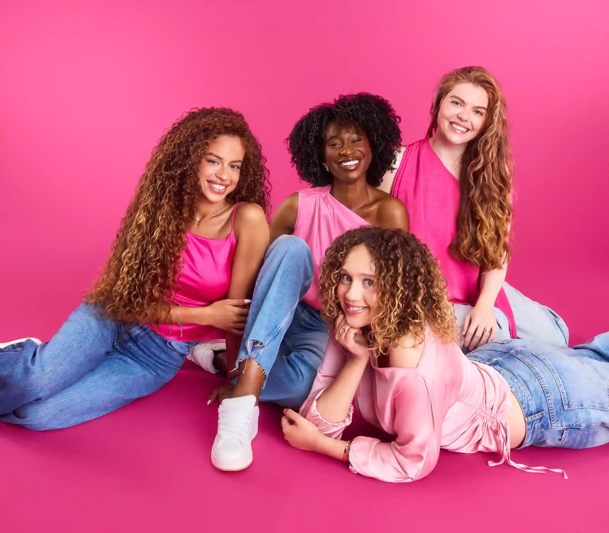 4 women with textured hair on a pink background